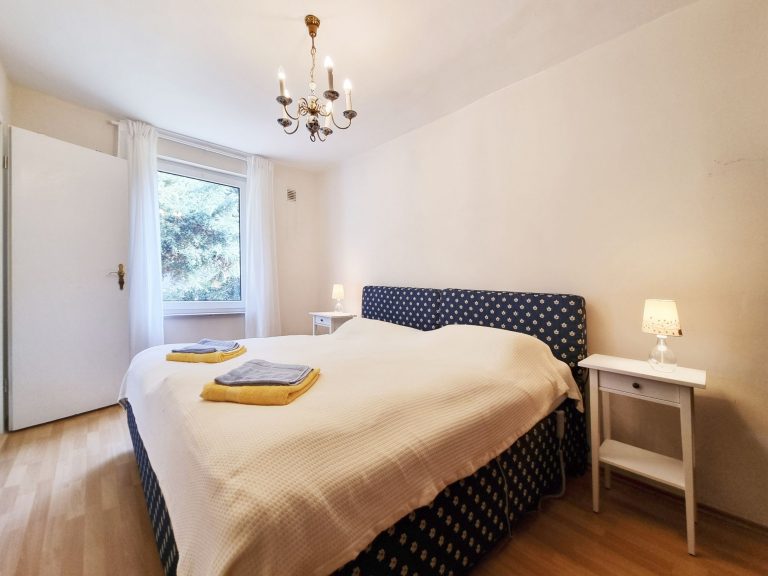 Großes Doppelbett im Schlafzimmer 1. Der dichte, immergrüne Wacholder direkt vor dem Fenster bietet angenehmen Sichtschutz.