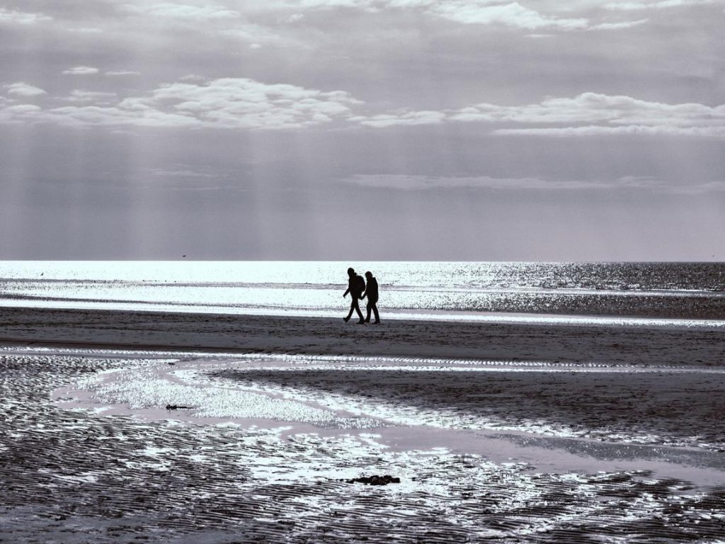 Paar spaziert am Strand bei ruhiger Abendstimmung an der Ostsee