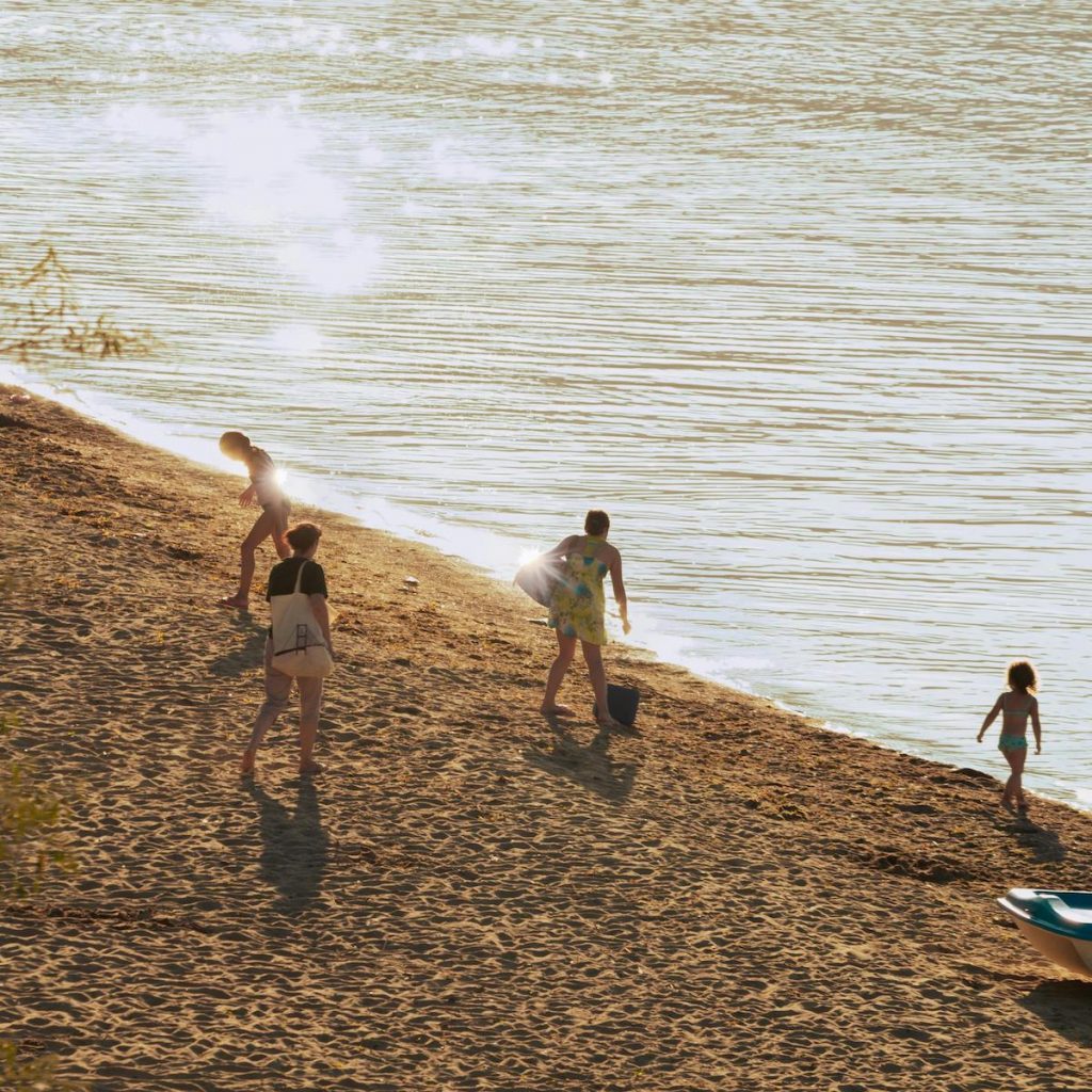 Familie mit Kindern an einem ruhigen Sandstrand des Stettiner Haffs im warmen Sommerlicht
